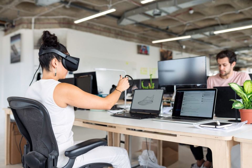 Mulher usando um headset de realidade virtual em um escritório moderno, em um contexto de design e inovação